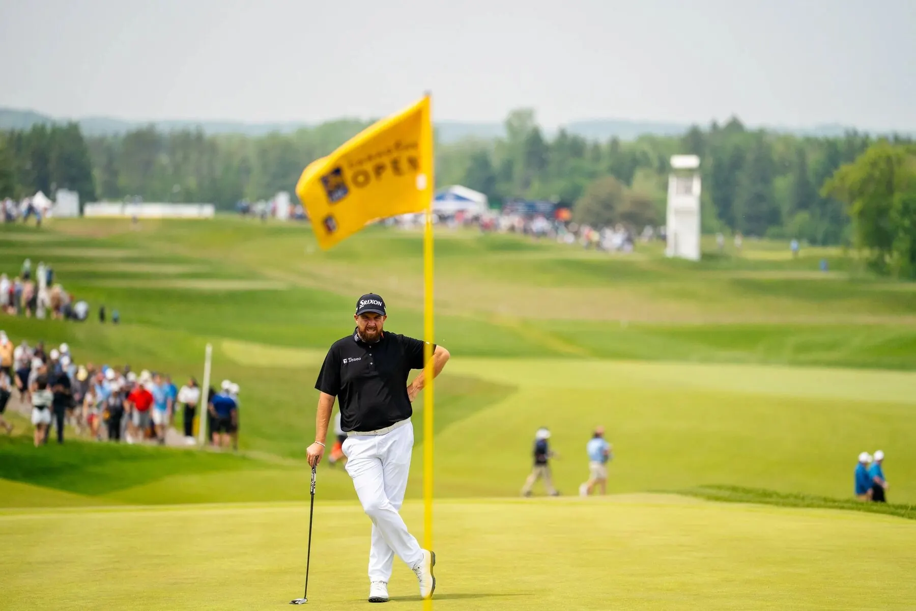 Golfer at the flag with gallery in the background