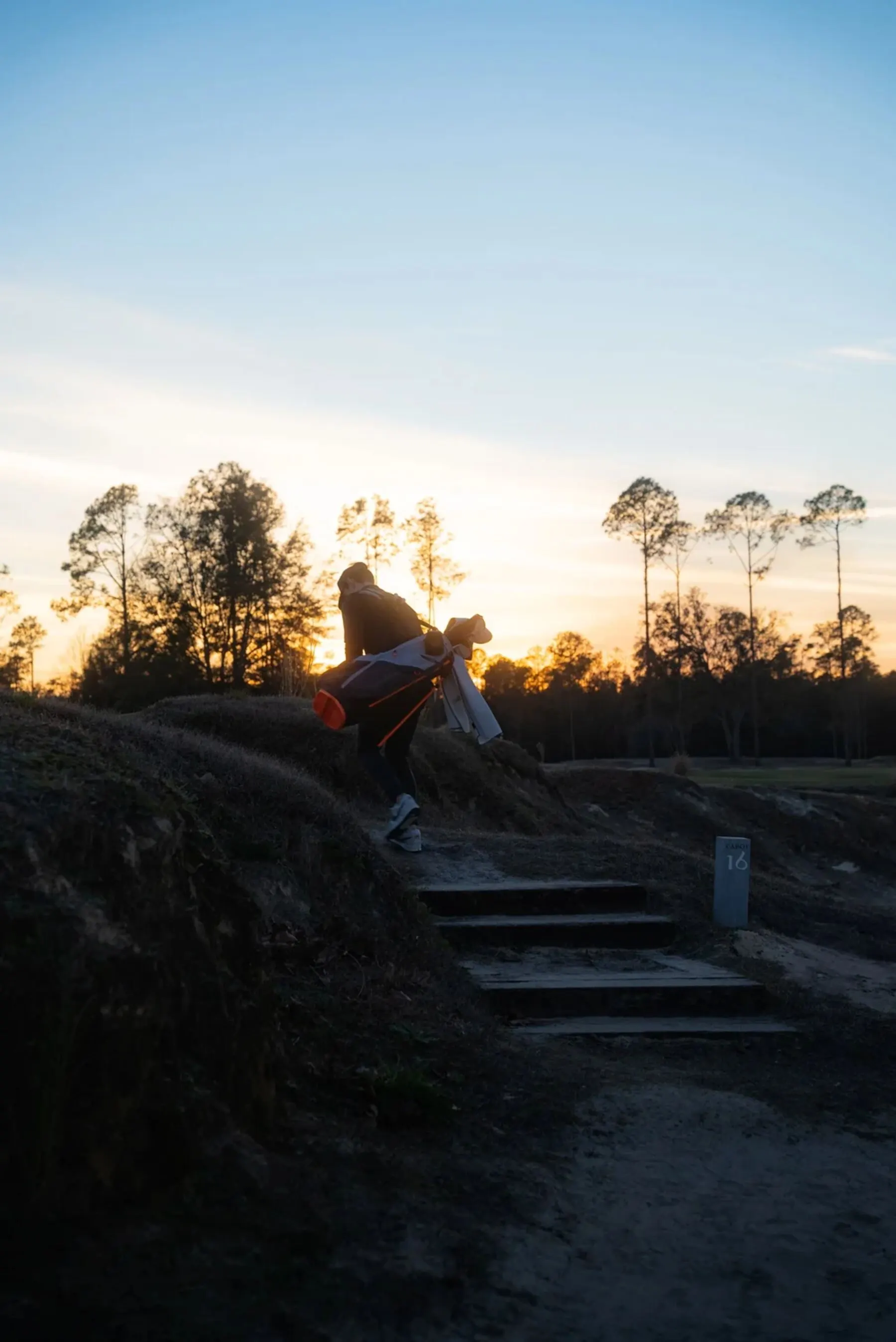 Golfer climbing course steps at dusk