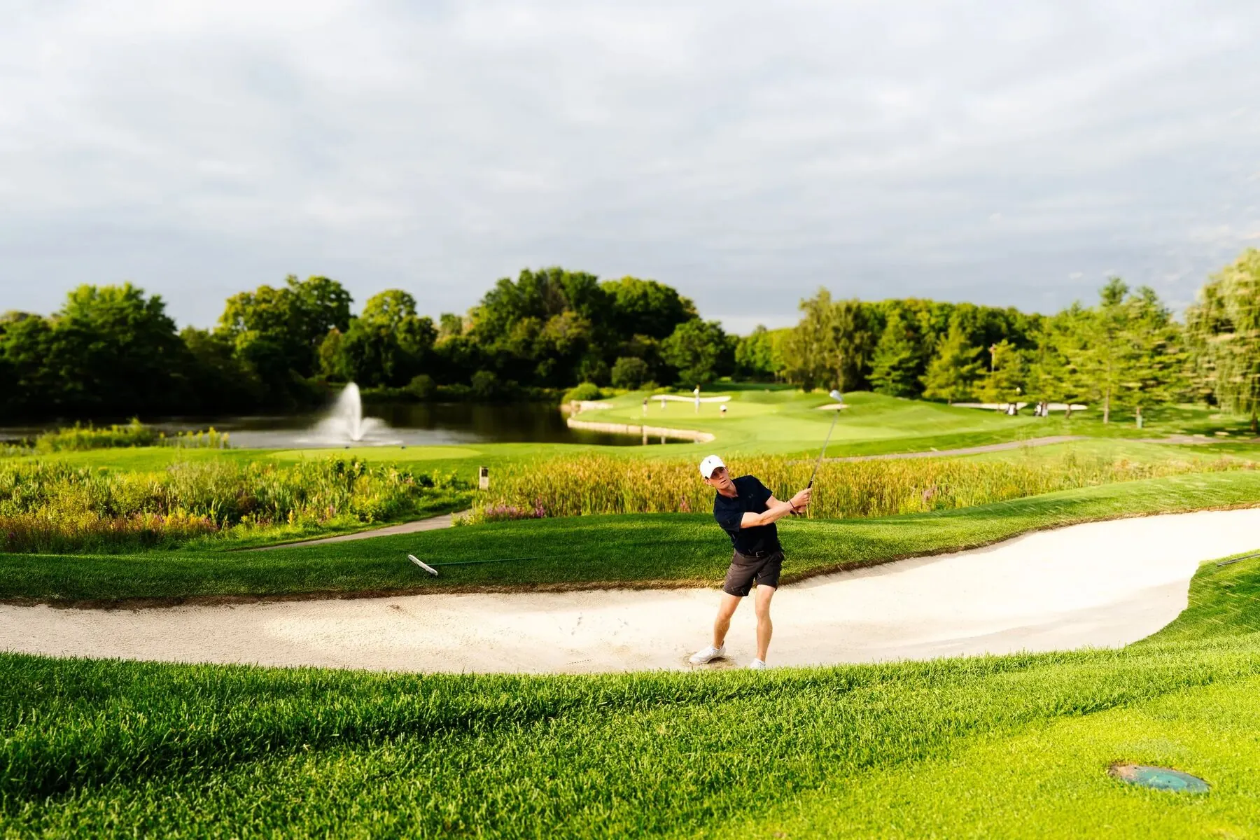 Golfer in a bunker beside a fountain pond at Deer Ridge