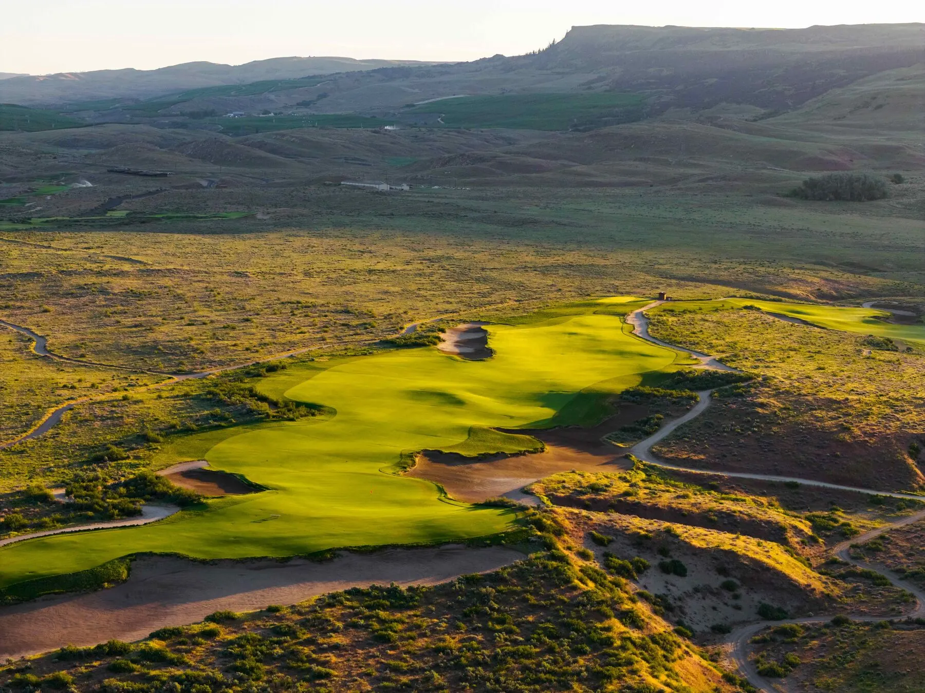 Green and bunkers set against the desert hills