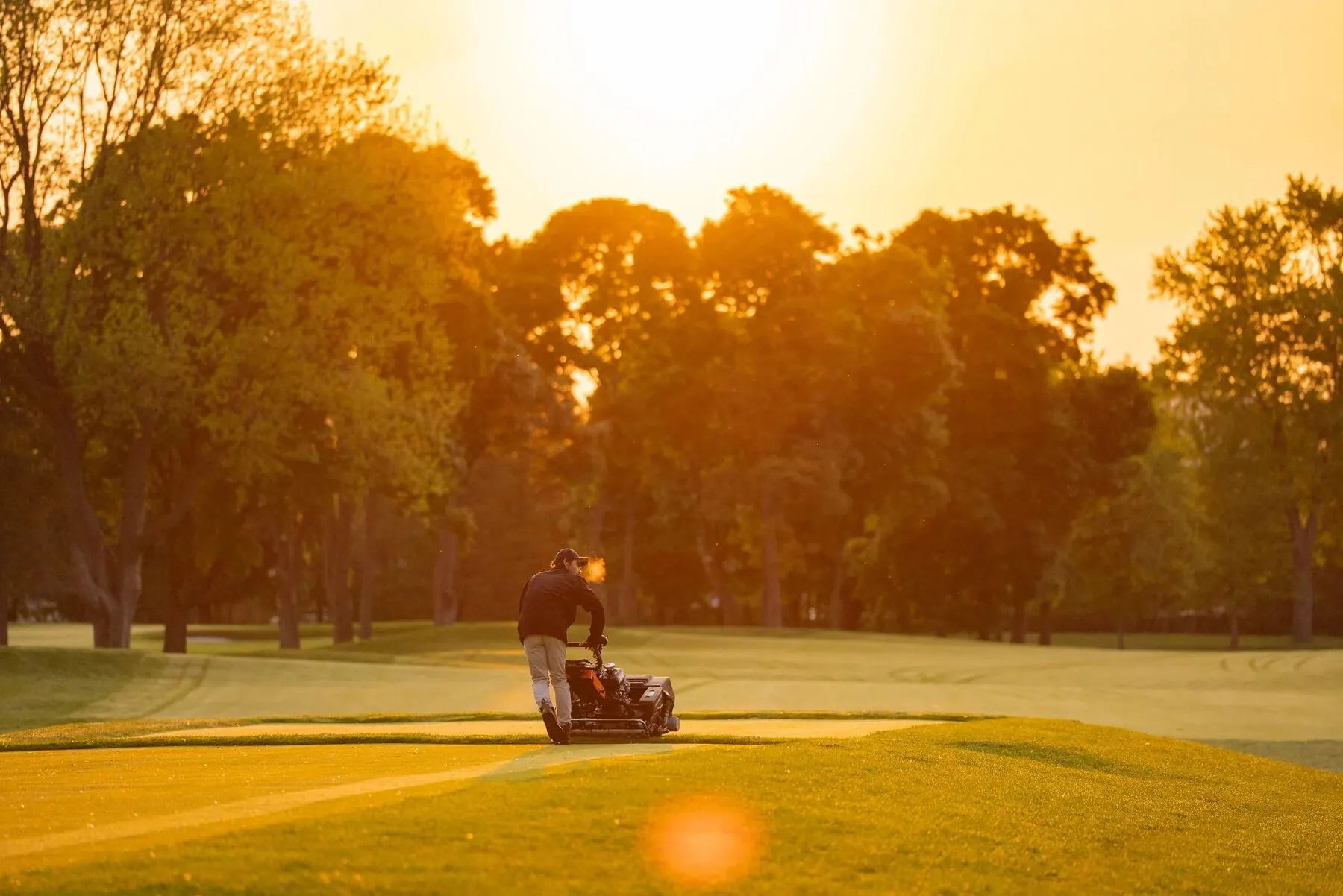 Greenkeeper preparing the course at golden hour